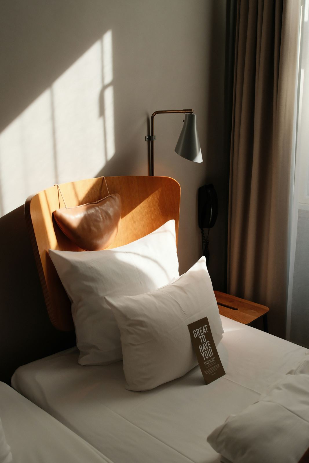 Hotel bed with white pillows and linen in daylight