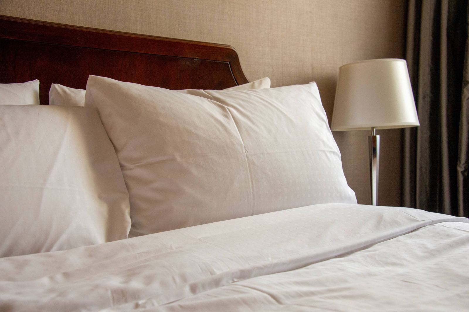 Stacked hotel pillows on a made-up bed
